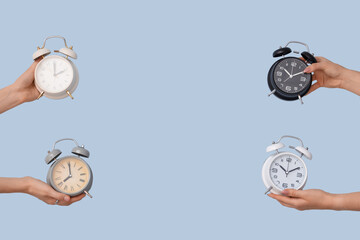Hands holding different alarm clocks on blue background