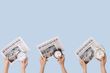 Hands holding different alarm clocks and newspapers on blue background