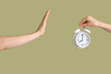 Hands holding alarm clock on green background