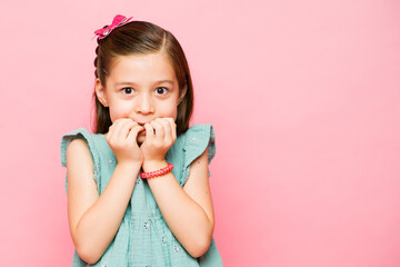 Cute little girl biting her nails feeling anxious