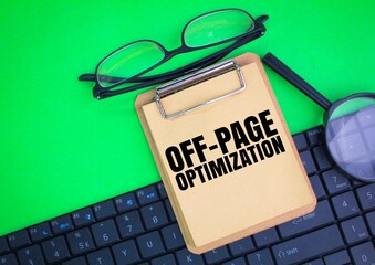laptop keyboard, magnifying glass, glasses and writing paper board with the word OFF-PAGE...