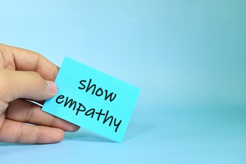 Show empathy reminder concept. Hand holding a bright paper message note.
