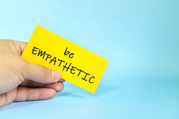 Be empathetic reminder concept. Hand holding a bright paper message note.