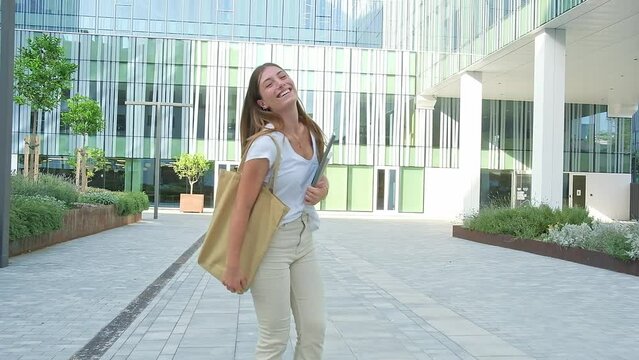 Rear view of happy female blonde college student walking, turning around smiling at camera. HD video.
