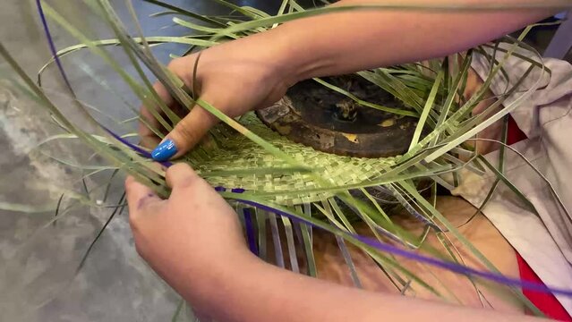 Female hand weaving skill using dried and dyed fragrant screwpine or vanilla grass to make a farmer&rsquo;s hat. Close up