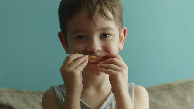 Portrait of a cute child, a little boy, who eats bread with chocolate spread. Concept of children with a sweet tooth who eat sweets in large quantities. 4K.