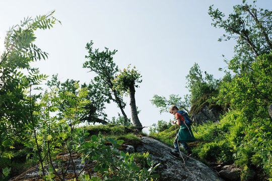 boy climbing the side of a cliff with a rope in Norway
