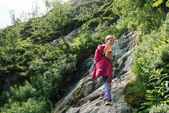 girl climbing up the side of a mountain with a rope