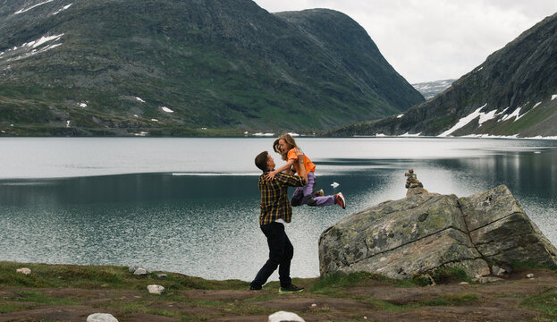 father catching his daughter jumping off a rock in Norway