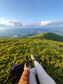 Girl with coffee in a thermos sits on top of a mountain range