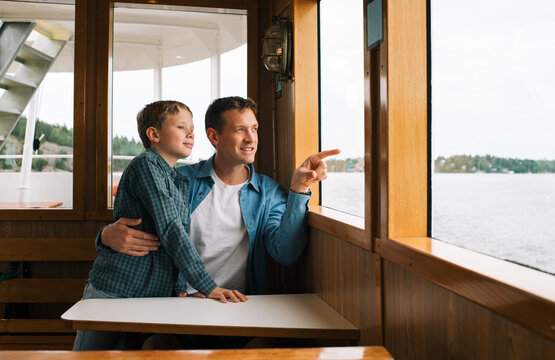 father and son looking out the window of a boat in Stockholm