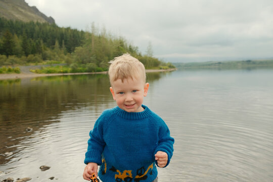 Toddler boy on shore of calm lake