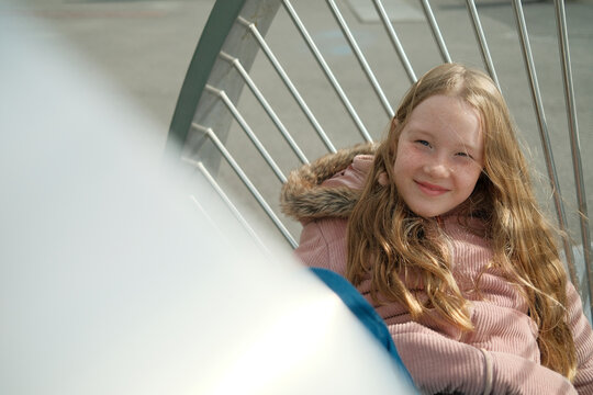 Charming girl on steel sculpture in city