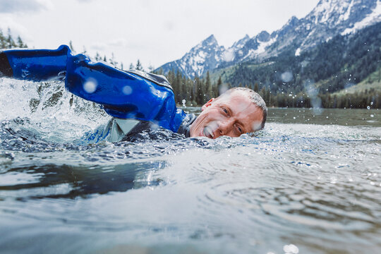 A middle aged male diver surfaces to take a breath.
