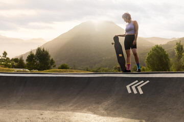 Woman skatepark skating at dawn with mountains in background