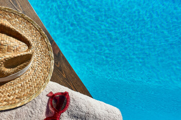 Summer concept. Accessories for vacation next to a pool, towel, sunglasses and straw hat. copy space. Horizontal frame.