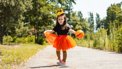 Happy Halloween! Cute little witch with a pumpkin outside