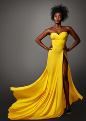 Fashion Dark Skin Woman in Yellow Silk Dress flying over Gray. African Model with Afro Curly Hair Style in Long Evening Gown. Stylish Lady Portrait - 648803719