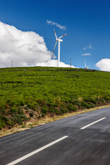 Windmill turbine with a blue sky and green field