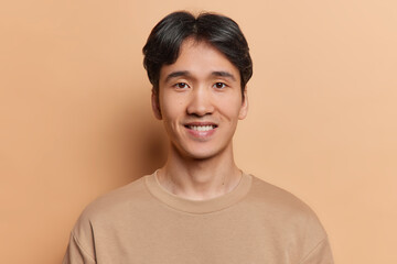 Portrait of handsome dark haired man smiles positively dressed in casual t shirt being satisfied...