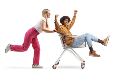 Caucasian young female pushing a shopping cart with an african american guy inside