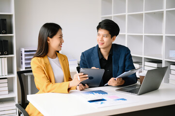 Two  Asian business  man and woman workers talking on the smartphone and using laptop Professionals in Teamwork  Finance, Marketing, and Success