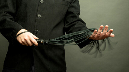 male dominant holds a leather whip Flogger for hard BDSM sex with spanking