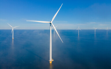 Windmill park with low hanging foggy clouds and a blue sky, windmill park in the ocean aerial view with wind turbine Flevoland Netherlands Ijsselmeer. Green Energy production in the Netherlands - obrazy, fototapety, plakaty