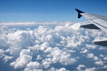 Fototapeta premium Aerial view of the thick and dramatic clouds from the airplane window. Airplane above clouds. Creative background for design. Flying, traveling and holidays concept. 