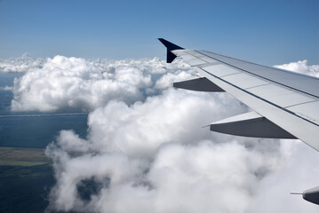 Aerial view of the thick and dramatic clouds from the airplane window. Airplane above clouds. Creative background for design. Flying, traveling and holidays concept. 