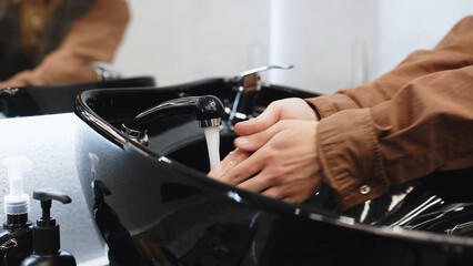 A man without a face washes his hands in a black sink. Close-up. Concept of hygiene, cleanliness.