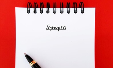 Red notebook with handwriting SYNOPSIS, means a brief summary, outline view of story, overview of...