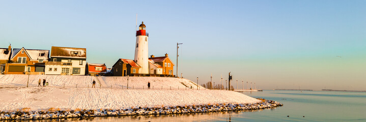 Lighthouse of Urk Netherlands during sunset in the Netherlands during winter with snow white landscape - obrazy, fototapety, plakaty