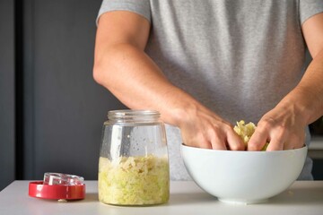 Unrecognizable man preparing homemade sauerkraut or fermented cabbage. - obrazy, fototapety, plakaty