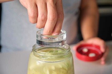 Unrecognizable man putting the fermentation weight on the fermentation jar to prepare homemade...