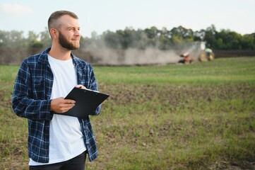 Agriculture. farmer working in a field in the background tractor plows ground in a field of wheat. farming agriculture concept. business farmer in the field