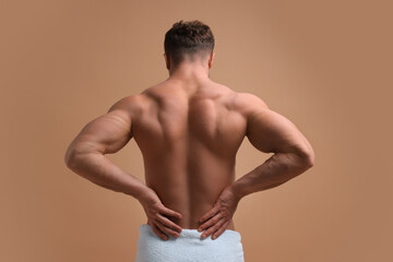 Fototapeta premium Man suffering from back pain on beige background, back view