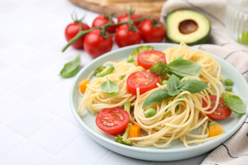 Plate of delicious pasta primavera and ingredients on white table, closeup