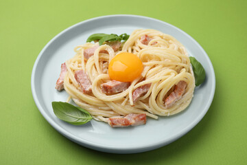 Delicious pasta Carbonara with egg yolk on light green background, closeup