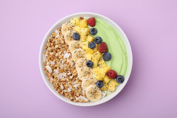 Tasty matcha smoothie bowl served with fresh fruits and oatmeal on violet background, top view. Healthy breakfast