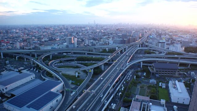HIGASHI OSAKA, JAPAN - JULY 2023 : Aerial view of high way, road junction and cityscape of downtown district in sunset. Japanese transportation, street traffic and urban city concept video.