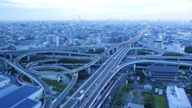 OSAKA, JAPAN - JULY 2023 : Aerial view of high way, road junction and cityscape of downtown. Japanese transportation, street traffic and urban city concept video. Long time lapse shot, dusk to night.