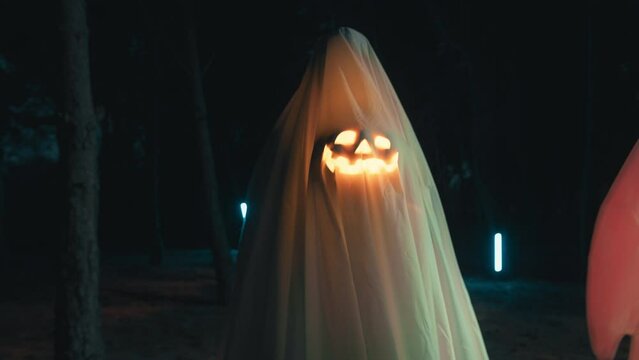 Halloween ghost in the night forest with glowing pumpkin
