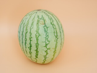 Striped watermelon on an orange background. Ripe watermelon close-up.