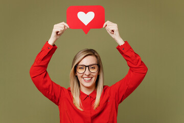 Young woman she wears red shirt casual clothes glasses hold heart form like icon sign from social network media feedback isolated on plain pastel green background studio portrait. Lifestyle concept.