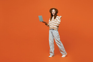 Full body young IT woman she wear striped sweater hat casual clothes hold use work on laptop pc...