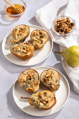 Baked pears with blue cheese, walnuts and honey on white plate closeup, perfect summer dish made of local fruits and affordable products, top view