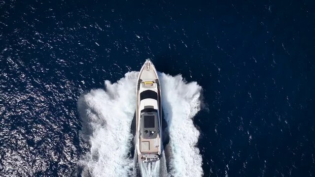 Aerial slow motion view of a luxury yacht cruising with high speed over blue ocean