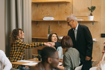 Mature business boss greeting his junior employees