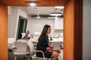 Obraz premium Happy brunette woman laughing while having a fun conversation with her teammates during break at work